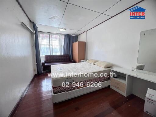 Spacious bedroom with bed, sofa, wardrobe, and dressing table