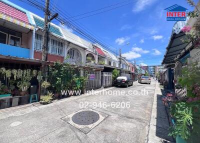 Street view of a residential neighborhood with terraced houses and parked cars