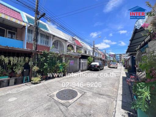 Street view of a residential neighborhood with terraced houses and parked cars