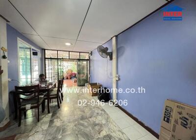 Living room with tiled floor, blue walls, ceiling fan, and table with chairs.