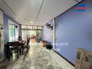 Living room with tiled floor, blue walls, ceiling fan, and table with chairs.