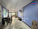 Living room with tiled floor, blue walls, ceiling fan, and table with chairs.