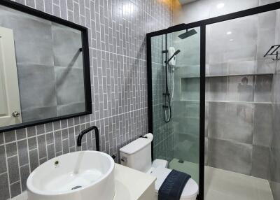 Modern bathroom with glass shower, tiled walls, and vanity