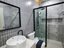 Modern bathroom with glass shower, tiled walls, and vanity