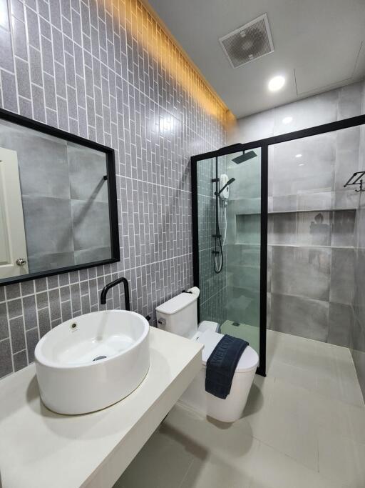 Modern bathroom with glass shower, tiled walls, and vanity