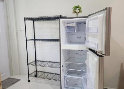 Kitchen space with open refrigerator and metal shelving unit