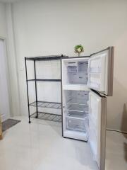 Kitchen space with open refrigerator and metal shelving unit