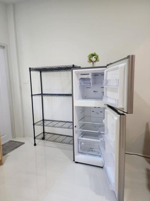 Kitchen space with open refrigerator and metal shelving unit