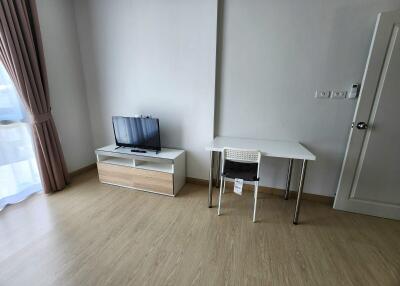 Living room with wooden flooring, a small TV stand with a flat screen TV, and a small desk with a chair