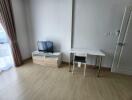 Living room with wooden flooring, a small TV stand with a flat screen TV, and a small desk with a chair