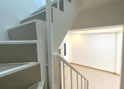 Staircase with white railings and beige steps leading to upper and lower floors