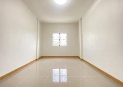 Spacious empty room with tiled flooring and a small window.