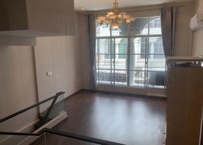 Spacious living area with large windows and modern chandelier.