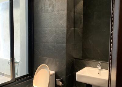 Modern bathroom with dark tiles, toilet, and sink