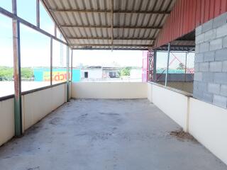 Spacious covered balcony with corrugated metal roof