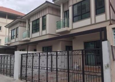 Exterior view of a modern residential building with balconies and a gated entrance