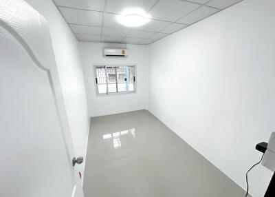 Empty small bedroom with white walls and tiled flooring