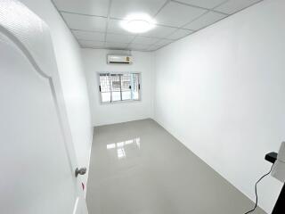 Empty small bedroom with white walls and tiled flooring