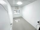 Empty small bedroom with white walls and tiled flooring