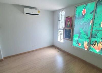 Spacious bedroom with wooden flooring and large window