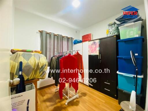 A bedroom with storage spaces, clothes racks, and wooden flooring