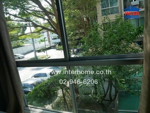 View from balcony overlooking parking lot and surrounding greenery