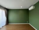 Spacious living area with wooden floor and green accent wall