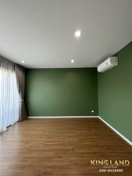 Spacious living area with wooden floor and green accent wall