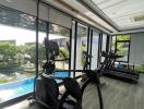 Home gym with a view of a pool and garden