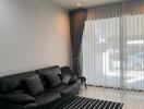 Modern living room with a black leather sofa and striped rug