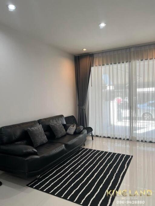 Modern living room with a black leather sofa and striped rug