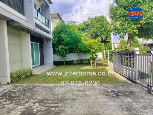 Front yard of a residential property with green lawn, concrete driveway, and trees