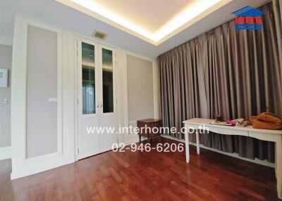 Empty room with wooden flooring, large window with curtains, and a built-in wardrobe.