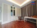 Empty room with wooden flooring, large window with curtains, and a built-in wardrobe.