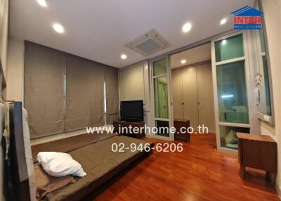 Spacious bedroom with wooden flooring, large windows, foldable bed, and built-in closet