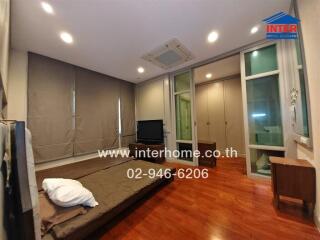 Spacious bedroom with wooden flooring, large windows, foldable bed, and built-in closet