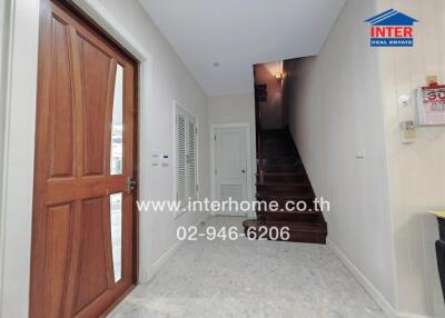 View of a hallway with a wooden door, stairs, and white walls