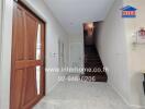 View of a hallway with a wooden door, stairs, and white walls