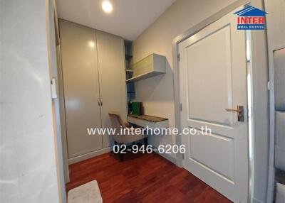 Home office with built-in desk and chair next to a large storage cabinet