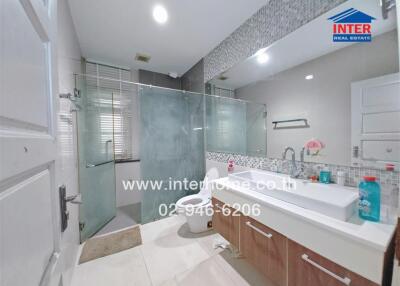 Modern bathroom with glass shower, vanity with sink, and toilet