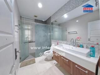 Modern bathroom with glass shower, vanity with sink, and toilet