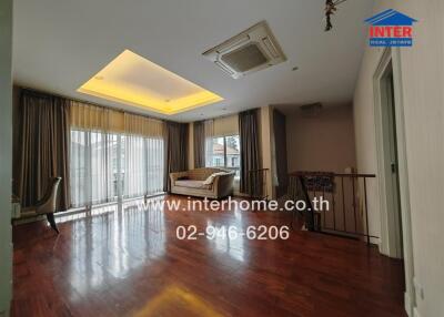 Spacious living room with wooden flooring, large windows, and a sofa