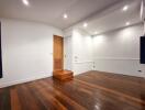 Empty main living area with wooden flooring and recessed lighting