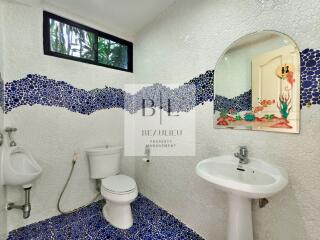 Colorful bathroom with unique mosaic tile design, containing a toilet, urinal, and sink