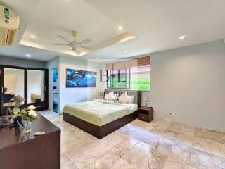 Spacious modern bedroom with a bed, dresser, and air conditioning