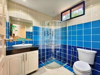 Modern bathroom with blue and white tiles, a sink, a shower, a toilet, and a window