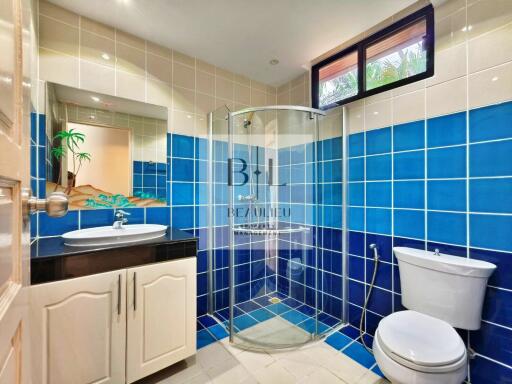 Modern bathroom with blue and white tiles, a sink, a shower, a toilet, and a window