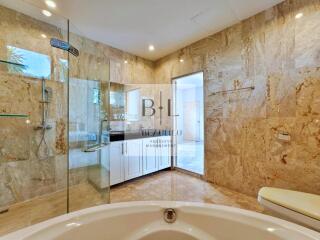 spacious luxury bathroom with marble walls and glass shower