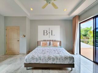 A spacious bedroom with a large bed, ceiling fan, and sliding glass door leading to a balcony