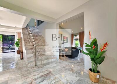 Spacious main living area with marble floors, staircase, and indoor plants